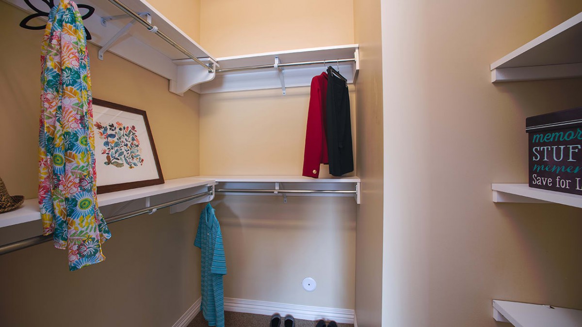 A simple closet with a few clothes and a framed picture on the shelf.