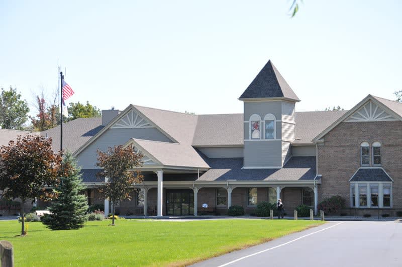 A modern church building with a steeple and spacious lawn.