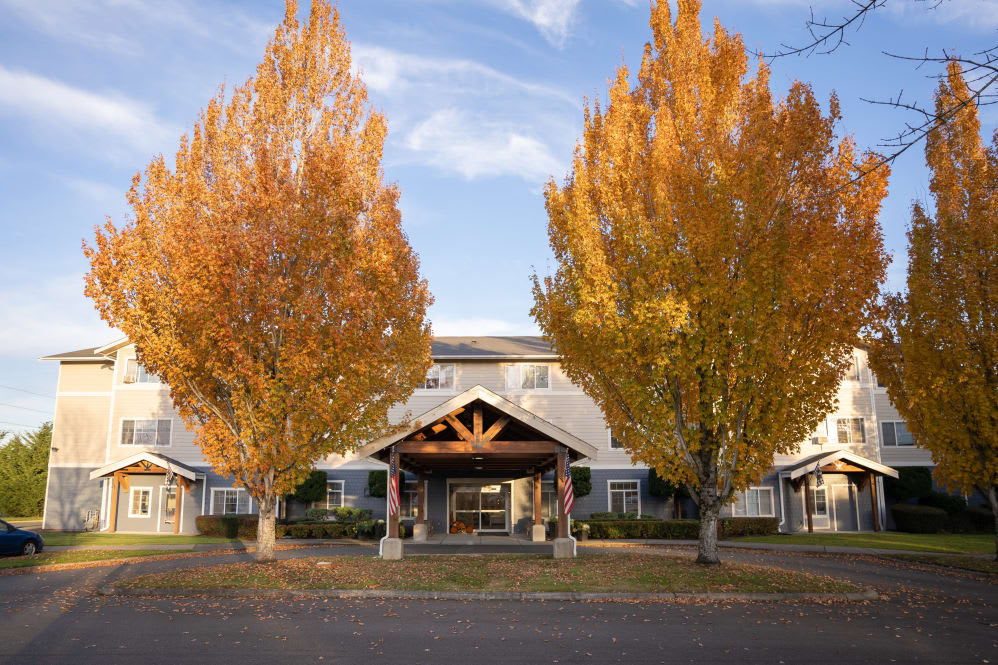 A building entrance surrounded by vibrant autumn trees with colorful leaves under a clear sky.