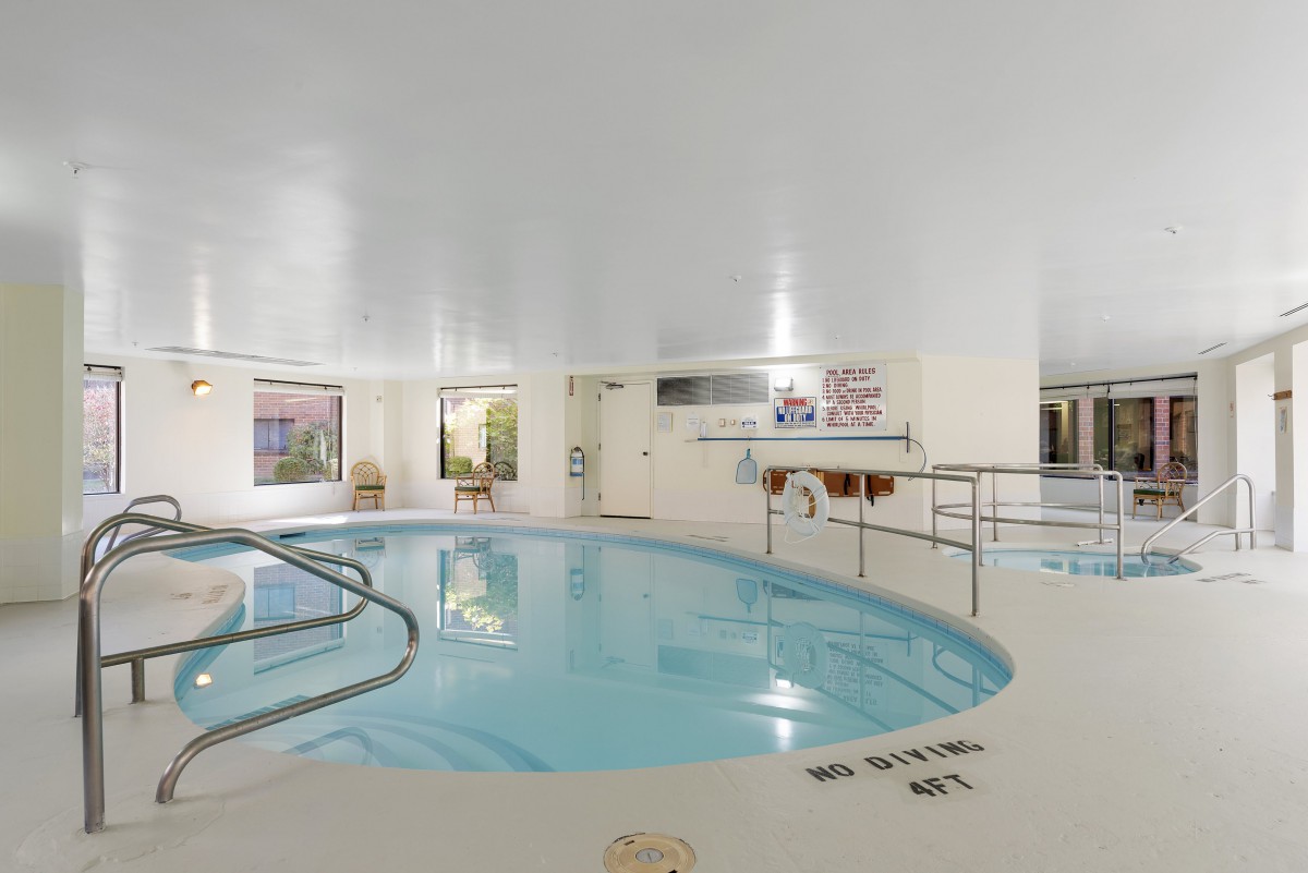 An indoor pool area inside a hotel, featuring a comfortable swimming space surrounded by windows.