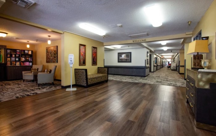A spacious hallway with wooden flooring, decorated with artwork and furniture.