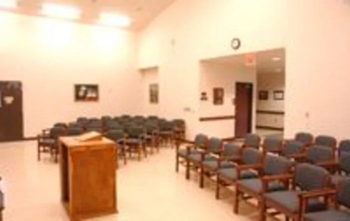 An empty meeting room with arranged chairs and a podium.