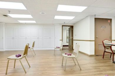 An empty meeting space with chairs arranged on a wooden floor.