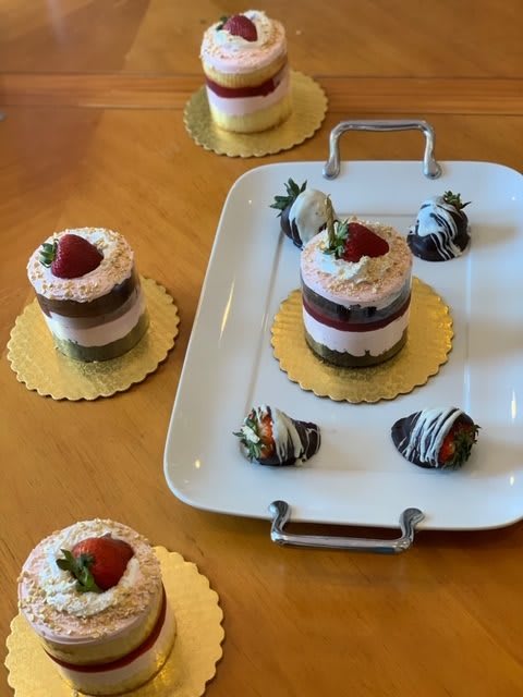 An assortment of mini cakes topped with strawberries and chocolate-covered treats displayed on a platter.