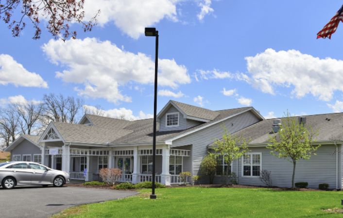 A suburban residential building with a well-maintained lawn and a clear sky in the background.