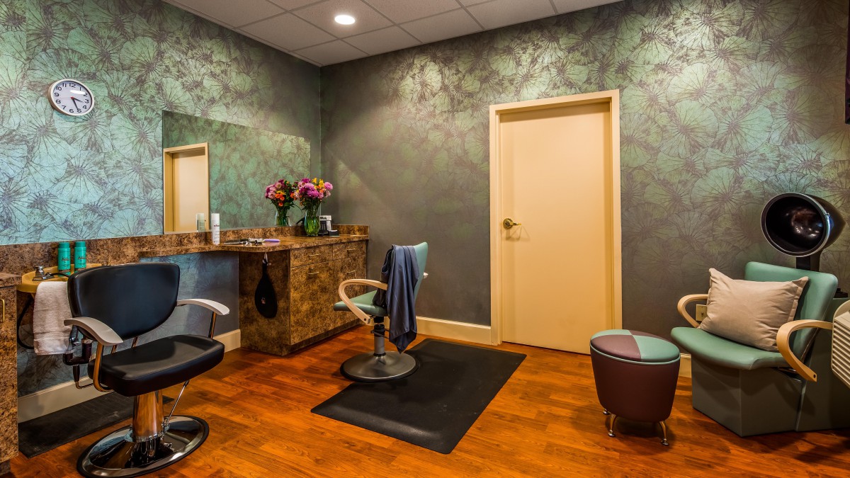 A modern salon interior with chairs, a mirror, and flowers on the counter.