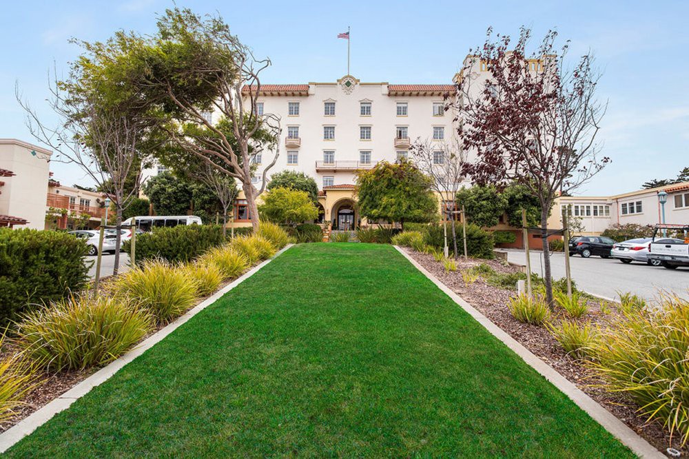 A well-maintained lawn and landscaping leading up to a grand hotel entrance.