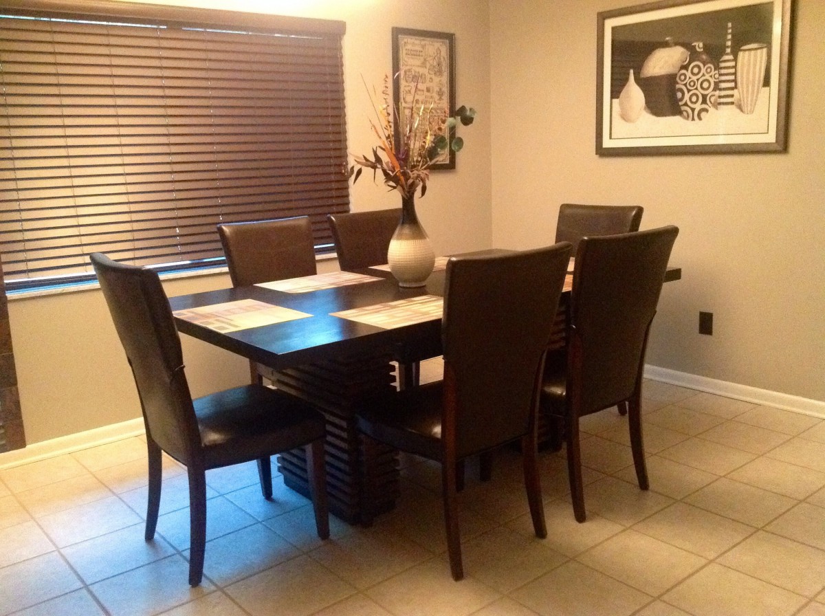 A cozy dining room with a dark wooden table and six matching chairs, accented by a decorative vase and wall art.