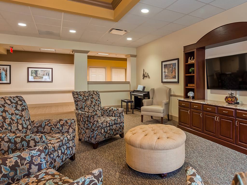 A comfortable lobby area featuring upholstered chairs, a round ottoman, and built-in shelving.