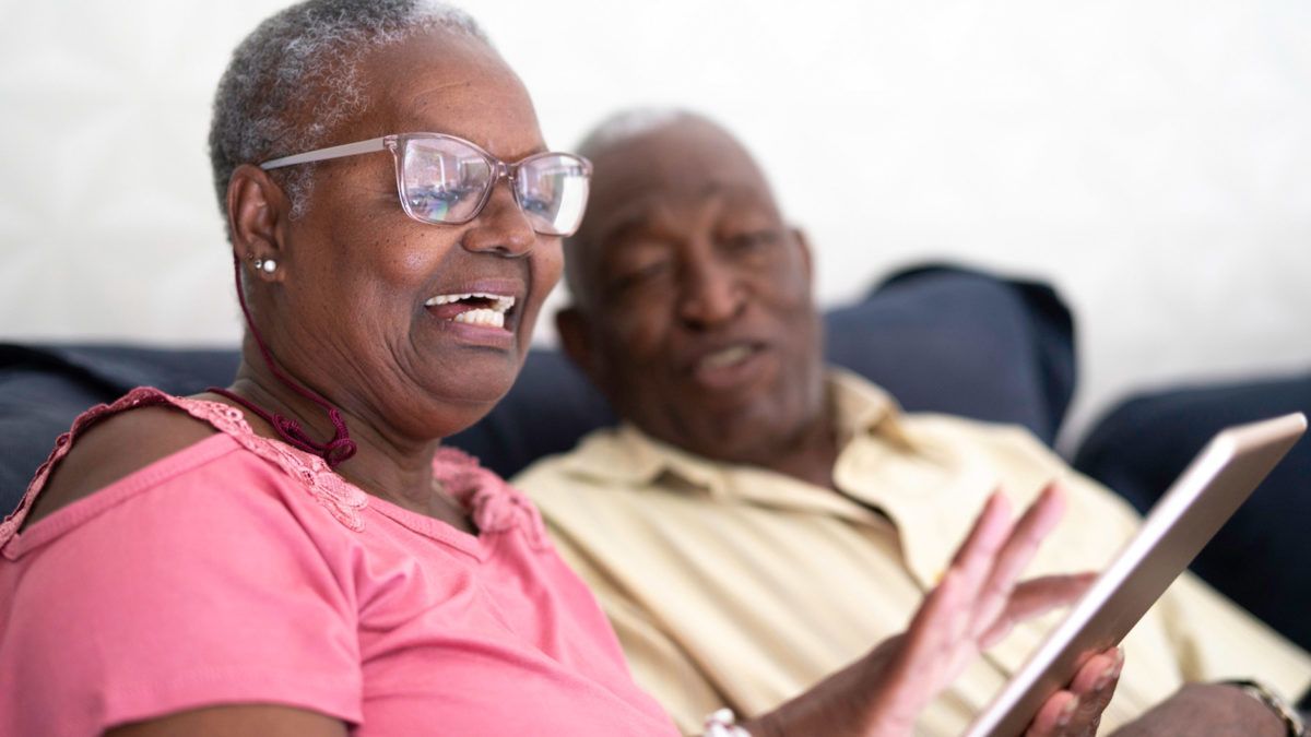 An elderly couple sitting together and smiling at home.
