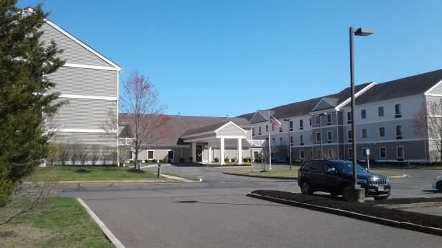 A hotel building with a driveway and parked cars under a clear blue sky.