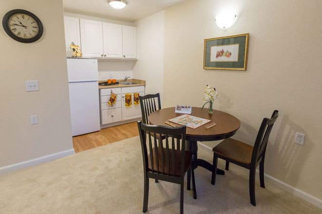 A cozy kitchen and dining area with a small round table, chairs, and essential appliances.