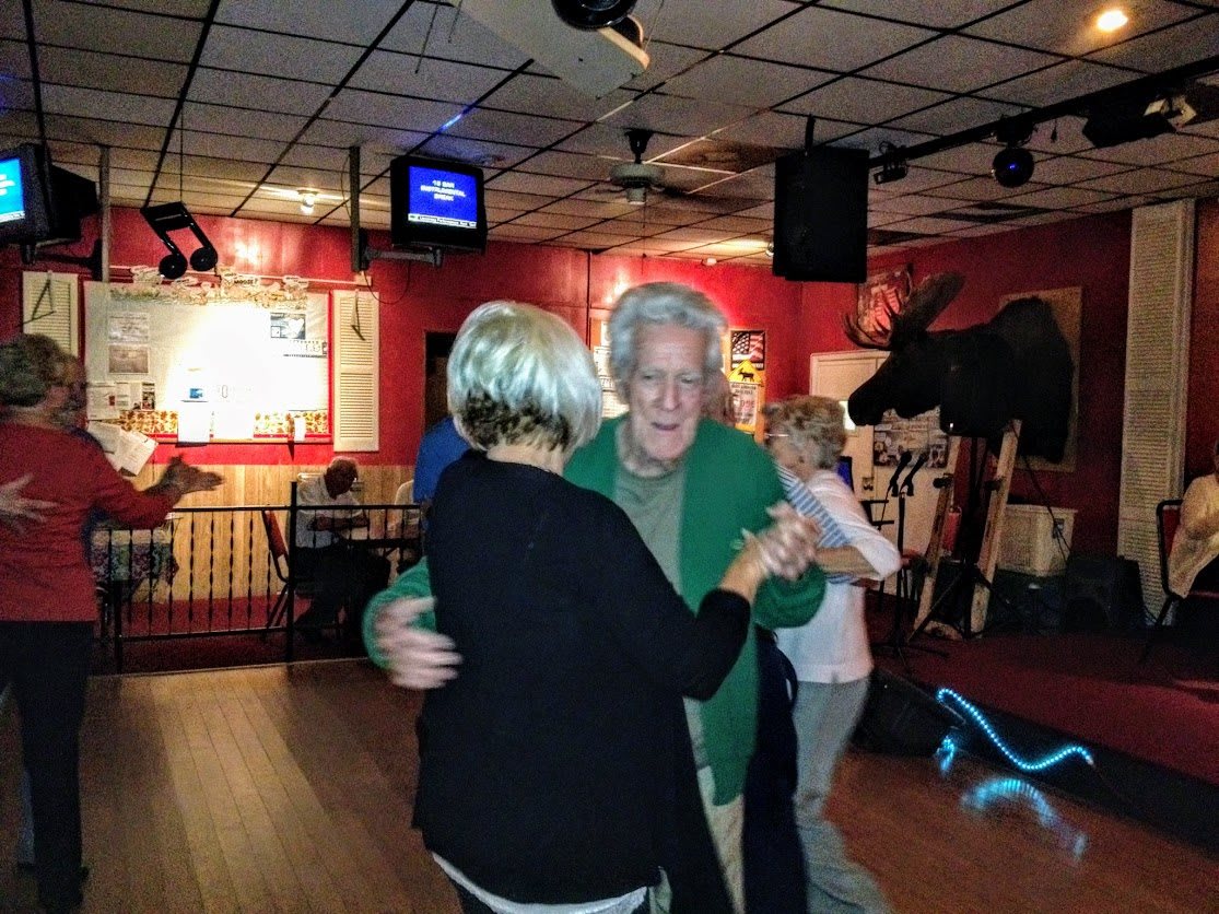 A couple enjoys dancing together in a lively bar setting.