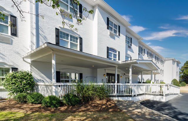 A modern residential building with a spacious porch and multiple windows.