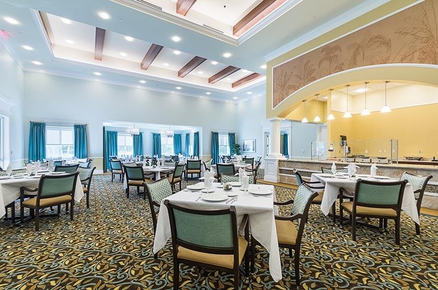 An elegant dining room with neatly arranged tables and chairs under bright lighting.