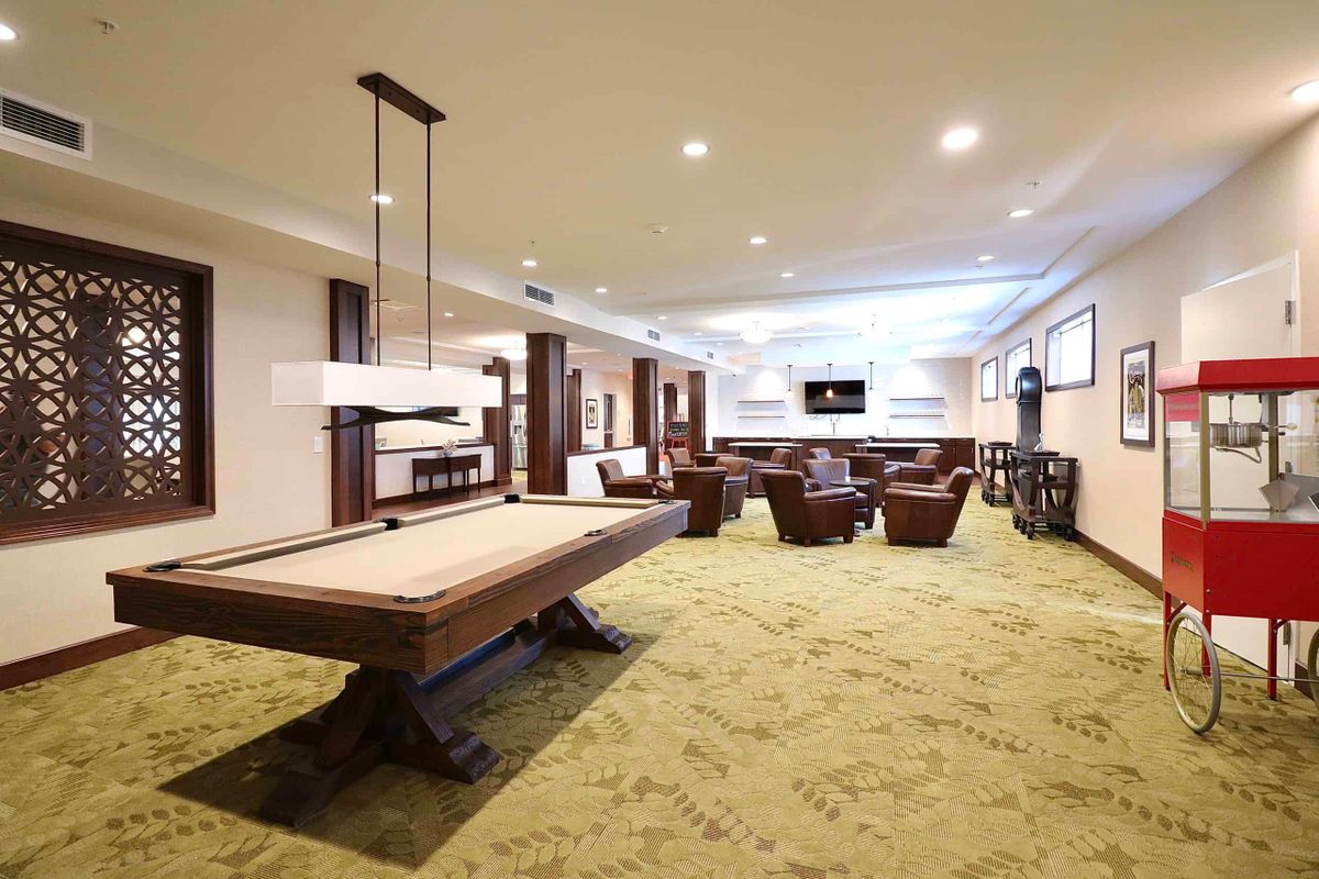 A spacious game room featuring a pool table and a comfortable lounge area.
