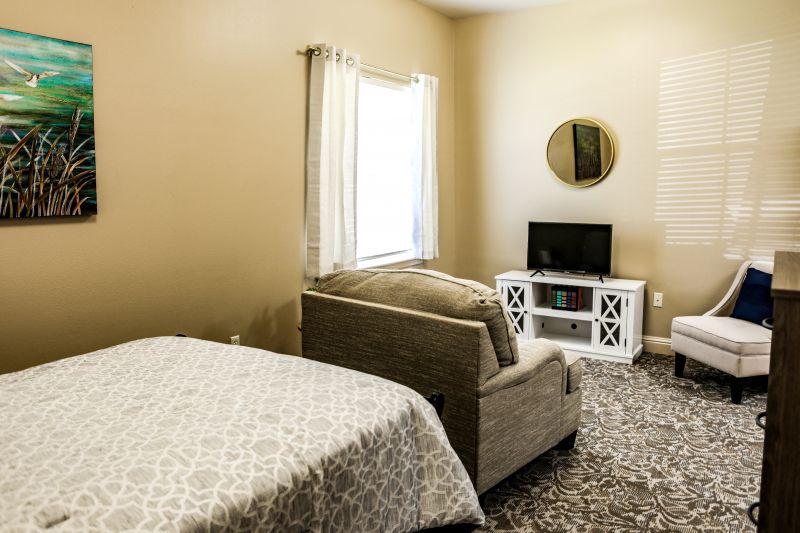 A cozy bedroom interior with a bed, sofa, and TV.