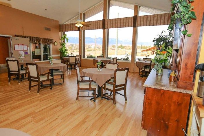 A spacious dining area with tables and chairs, featuring large windows that provide a bright and inviting atmosphere.