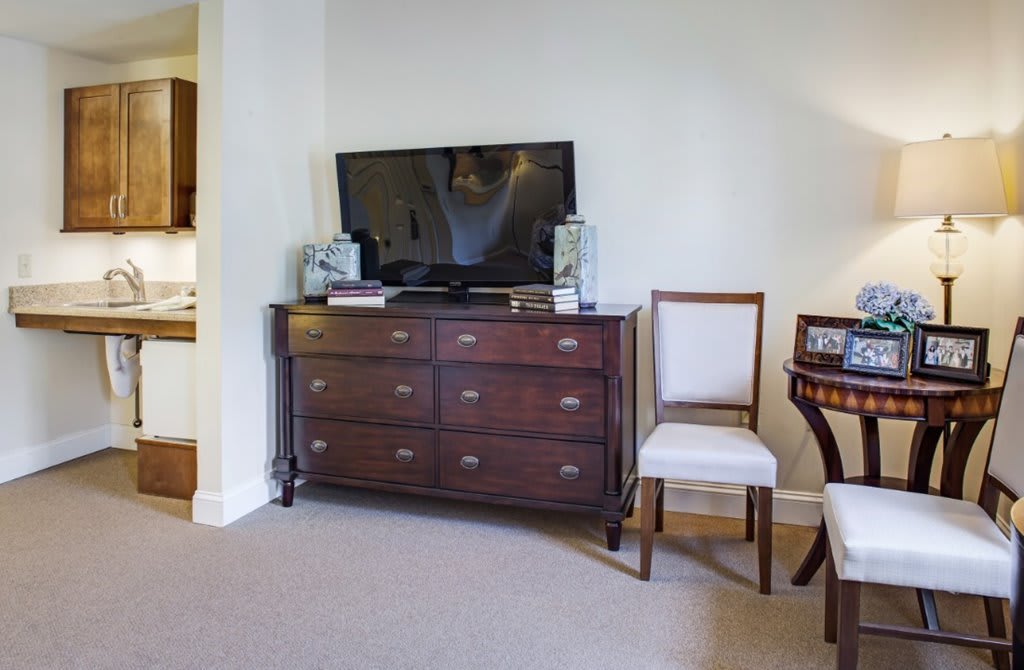 A living room setup featuring a television on a wooden dresser, accompanied by a chair.