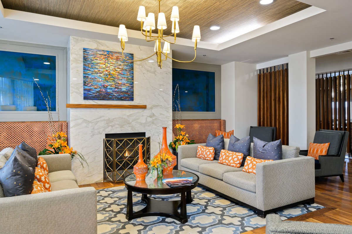 A modern living room with stylish furniture, featuring a cozy fireplace and elegant chandelier.