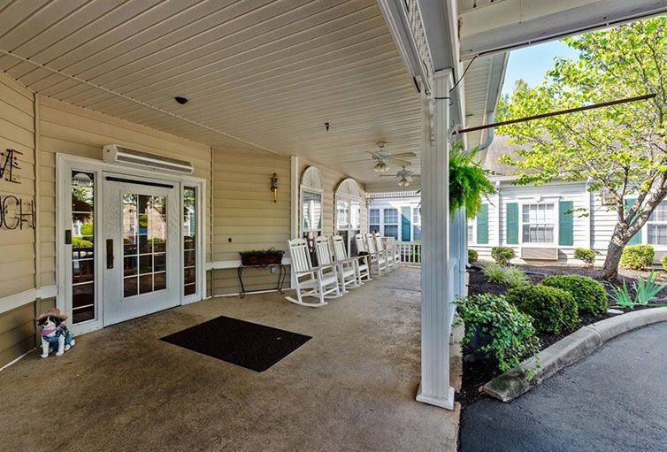 A cozy outdoor porch with rocking chairs and lush greenery.