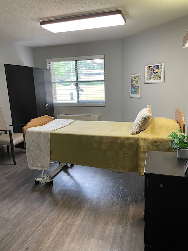 A well-lit hospital room featuring a hospital bed, furniture, and a decorative element.