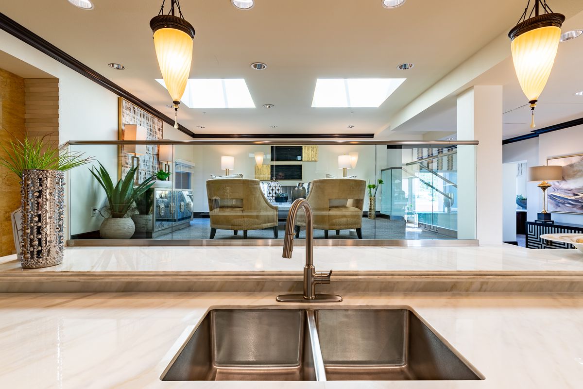 A modern kitchen with a stainless steel sink overlooking a stylish living area.