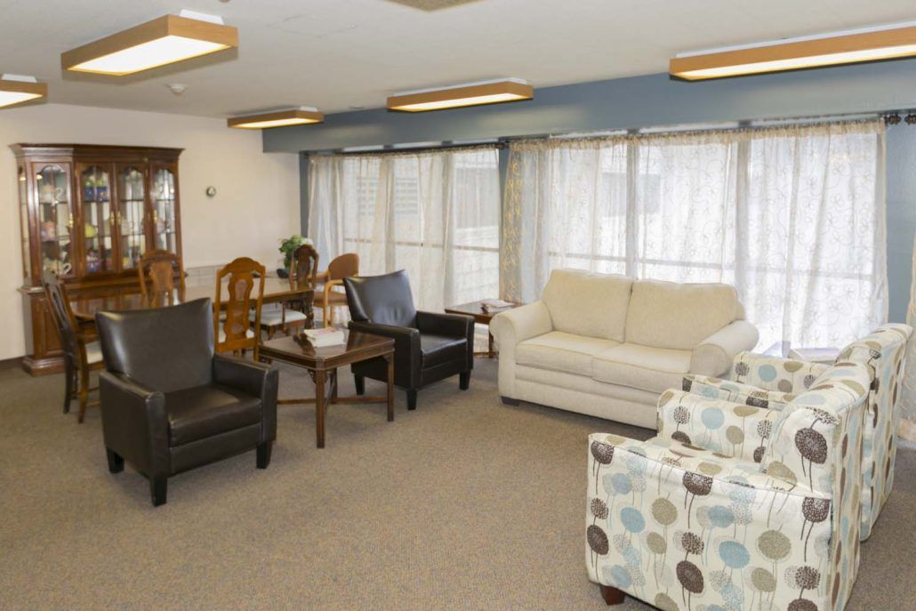 A cozy living room with sofas, chairs, and a dining table near large windows.