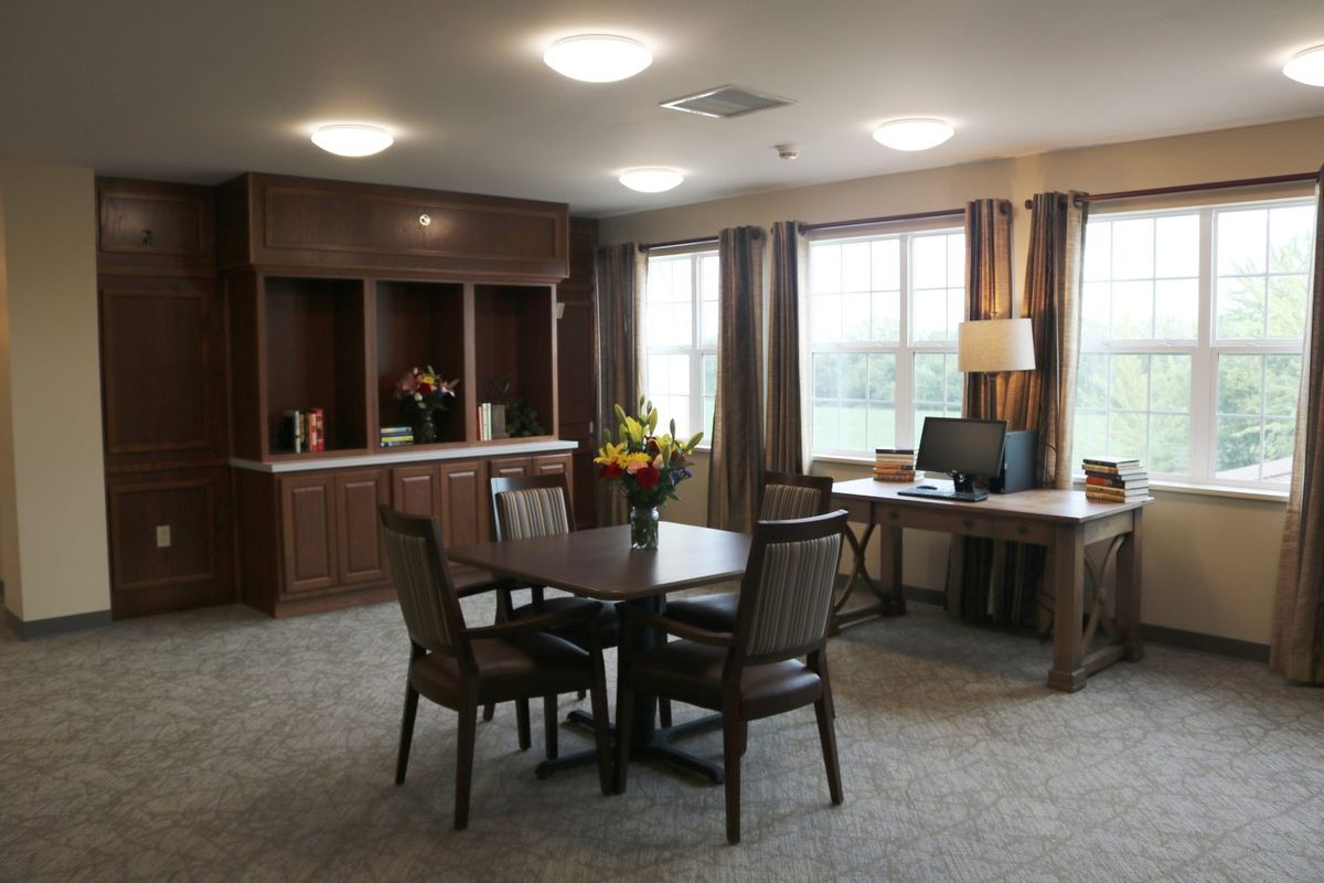 A well-lit office space with a table and chairs, computer, and decorative flowers.