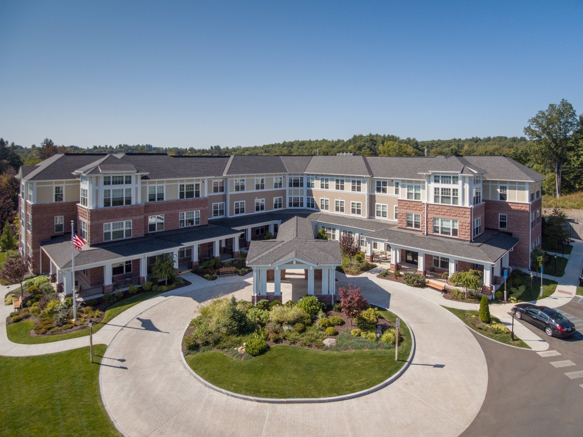 Aerial view of a modern residential building with well-maintained landscaping and a circular driveway.