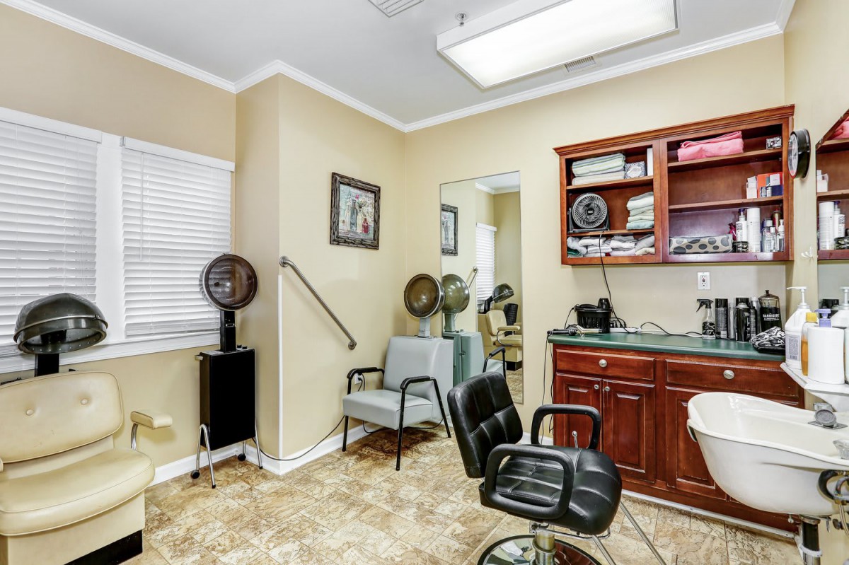 Interior of a hair salon with chairs, hair dryers, and cabinets.