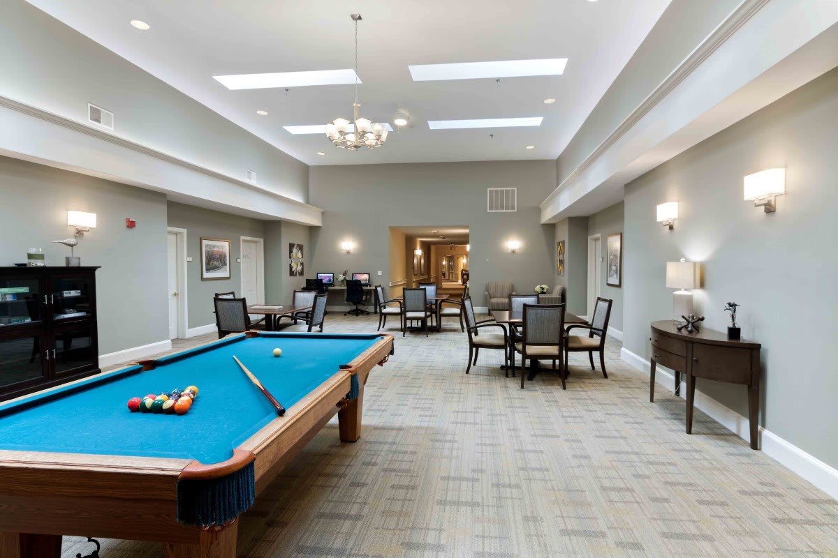 A spacious recreation room featuring a pool table and dining area with elegant lighting.