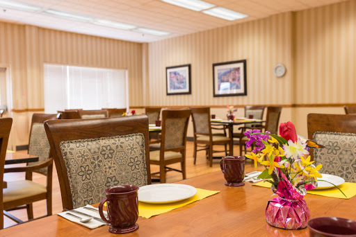 A cozy dining area set up for meals, featuring tables with floral arrangements and warm lighting.