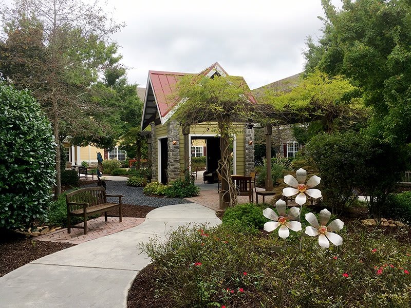 A serene garden pathway with lush greenery and a charming stone building.