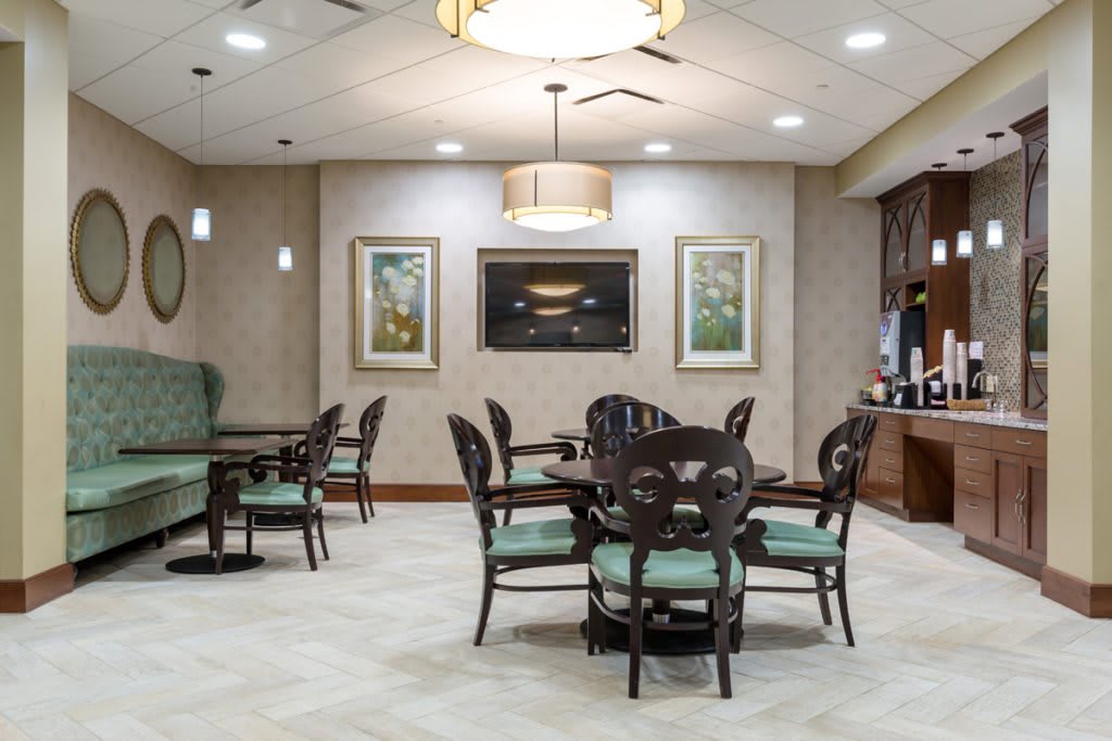 A cozy dining area with elegant furniture and ambient lighting, featuring artwork on the walls and a coffee station.