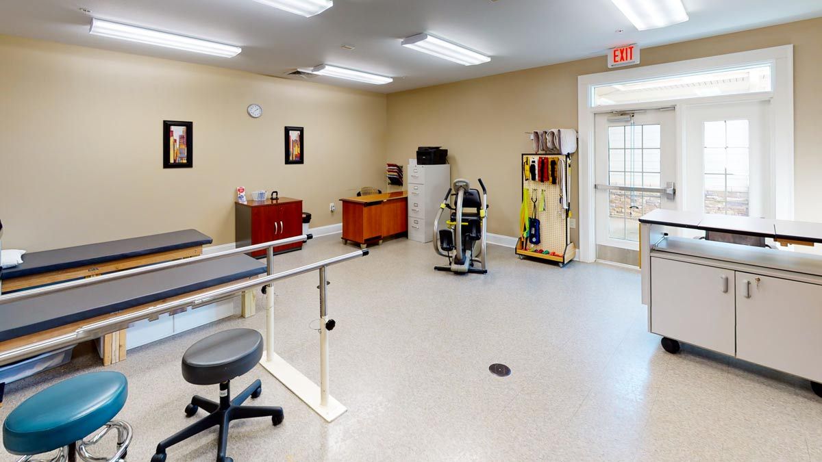 A well-equipped rehabilitation room featuring exercise equipment and parallel bars for physical therapy.