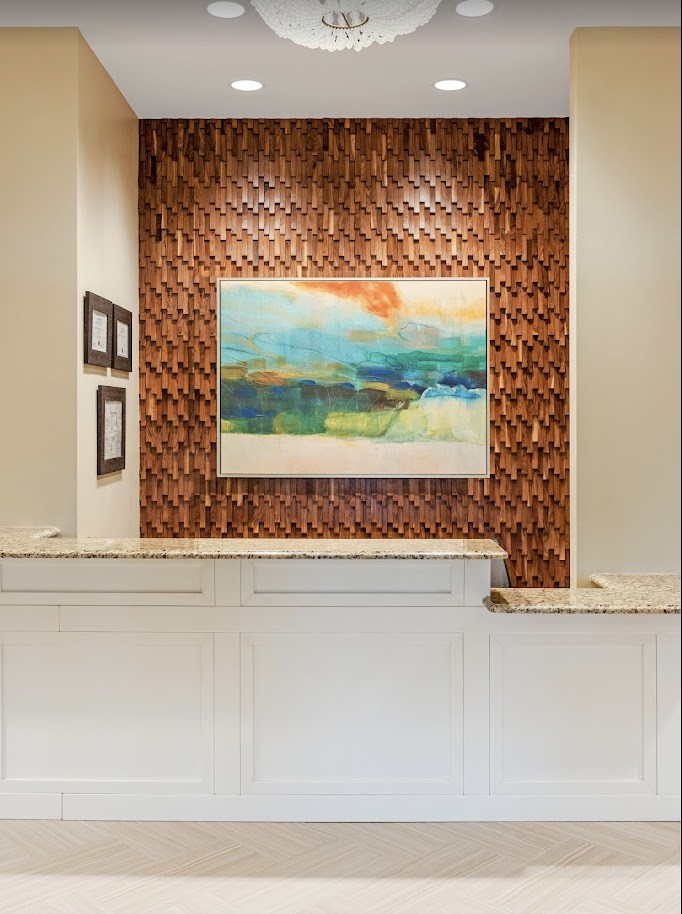 A modern reception area featuring a central artwork and textured wood paneling.