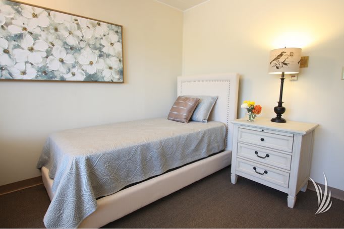 A cozy bedroom with a single bed, nightstand, and decorative elements.