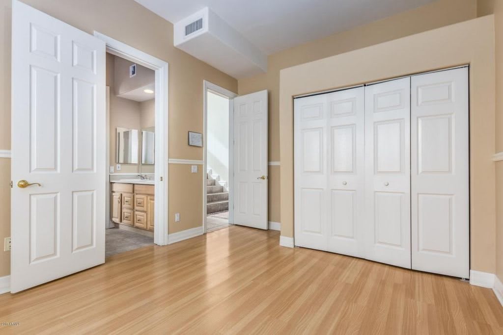 A bright, empty bedroom with a view of an adjoining bathroom and closet.
