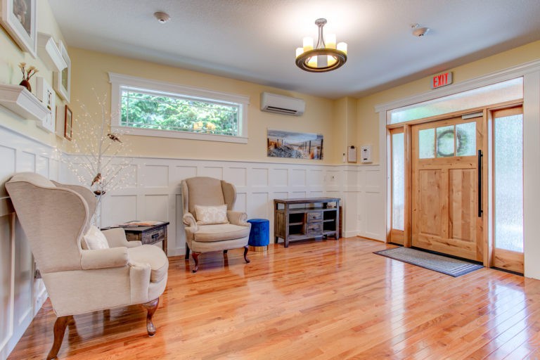A cozy living room with wooden flooring, featuring comfortable seating and warm lighting.