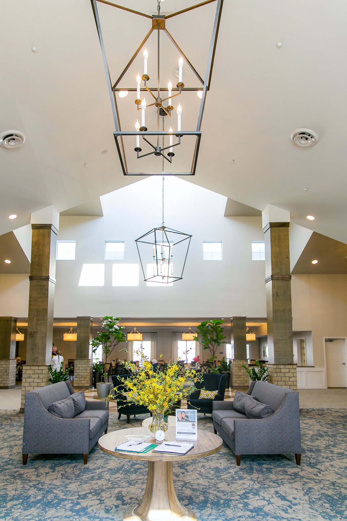 A modern lobby with comfortable seating and elegant lighting fixtures, accented by natural light and greenery.