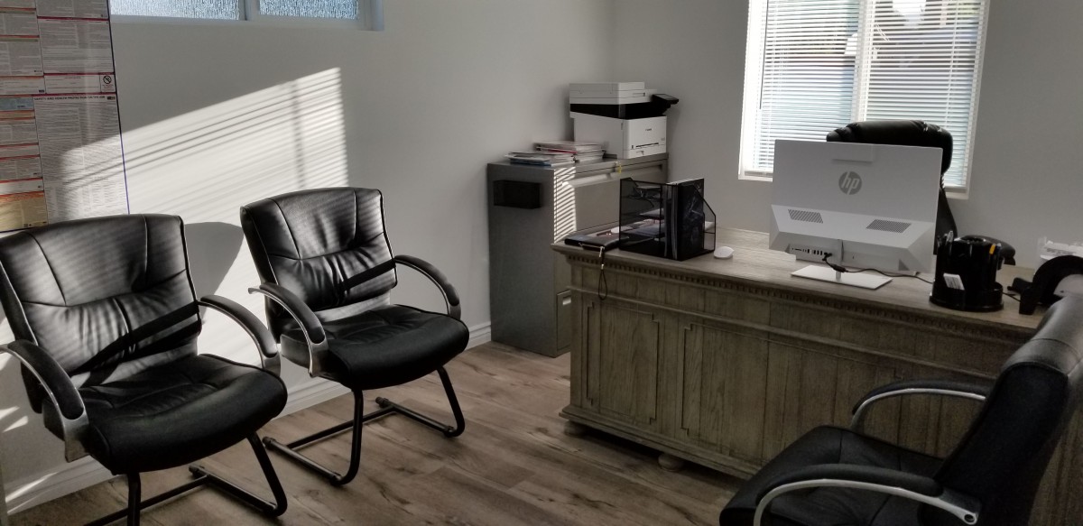 A small office space with a desk, chair, computer, and printer.