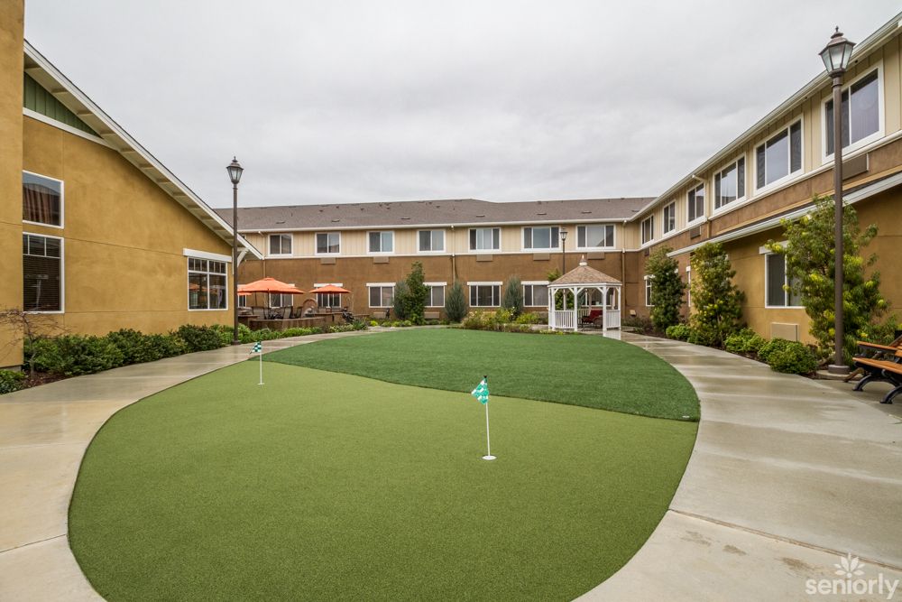 A well-maintained courtyard with a putting green and pathway, surrounded by a two-story building.