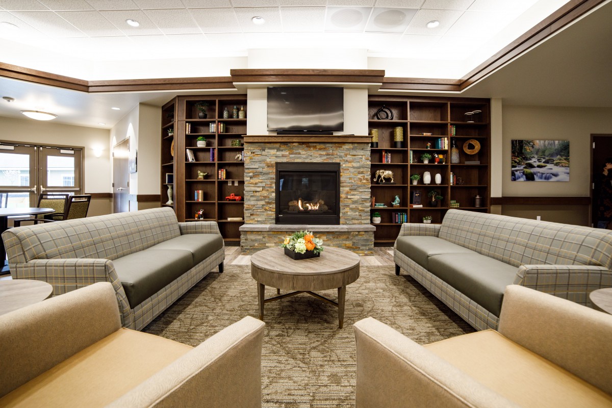 A cozy living room with a fireplace and comfortable seating surrounded by bookshelves.