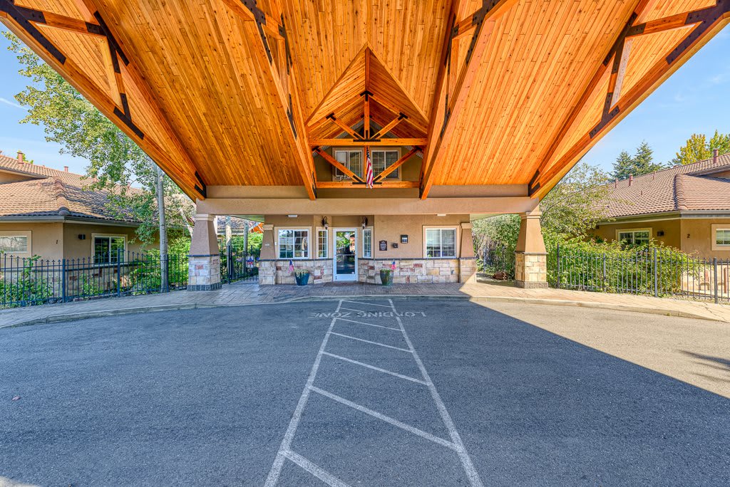 The image shows the entrance of a building with a wooden canopy and driveway.