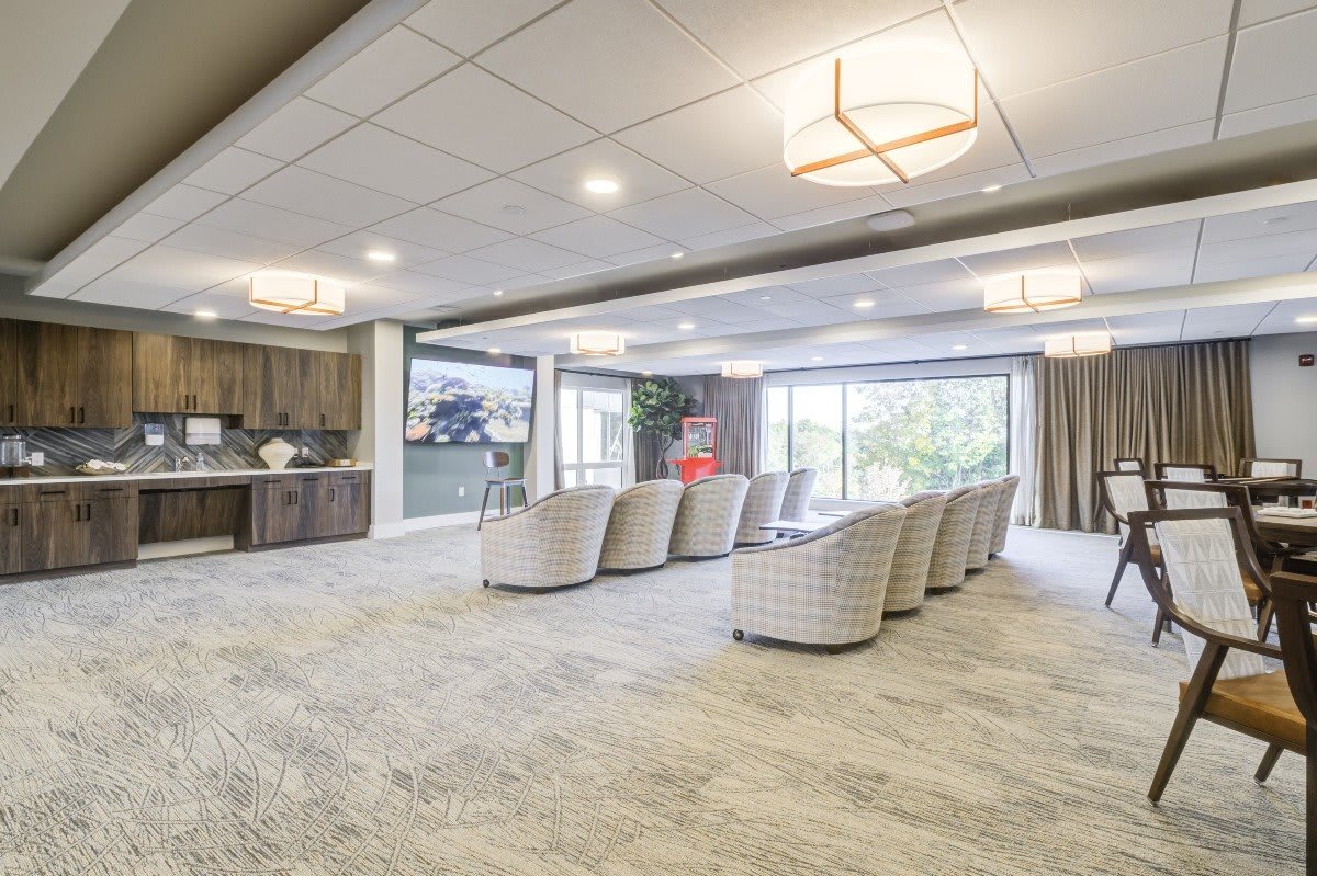 Spacious and modern living room with a comfortable seating area, large windows, and elegant ceiling lights.