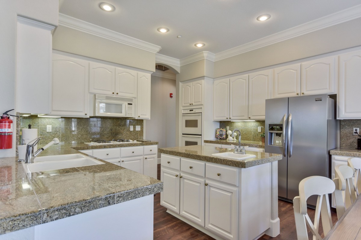 A modern kitchen with white cabinets and granite countertops.