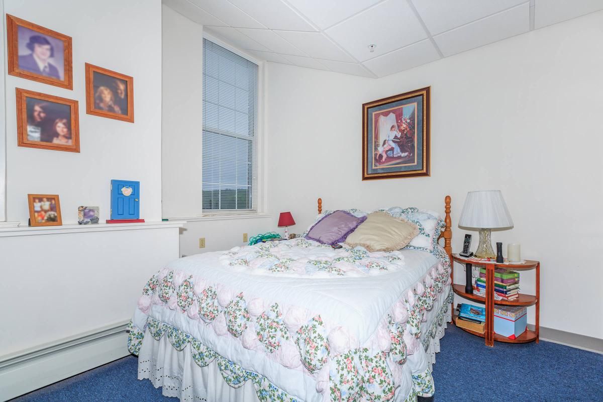Cozy bedroom with a floral bedspread, pillows, and framed artwork on the wall.
