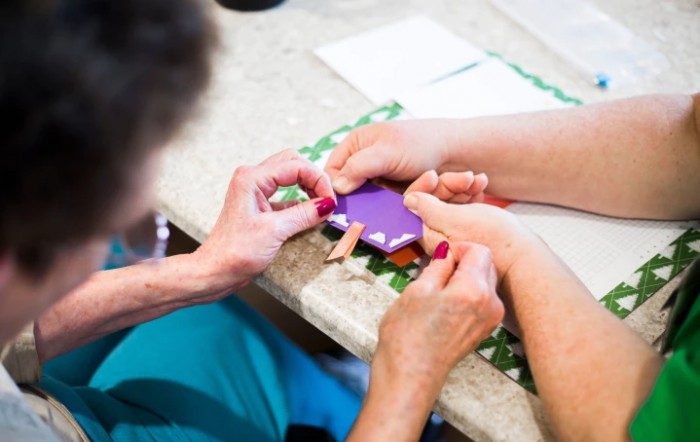A person receiving a manicure with purple nail polish.