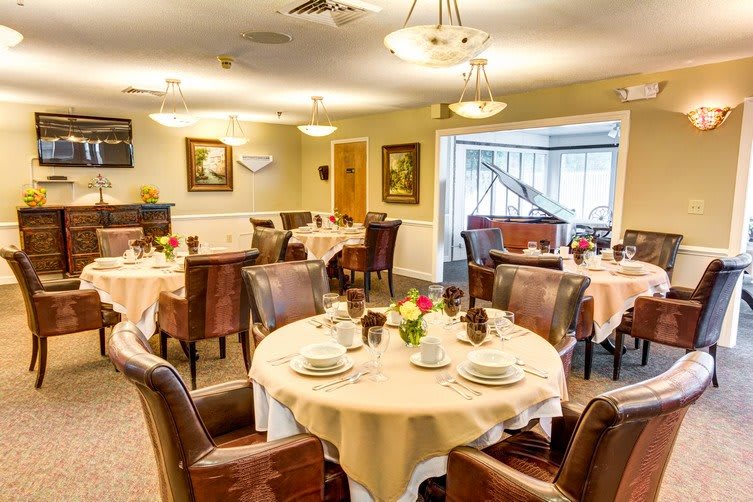 Elegant dining room setup with round tables and comfortable chairs, adorned with decorative elements and warm lighting.